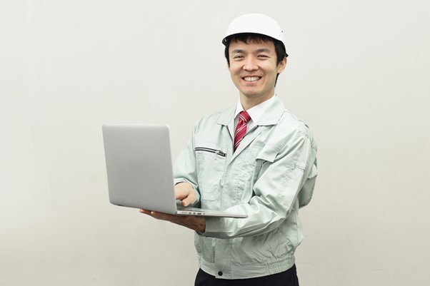 PCを操作する作業着姿の男性