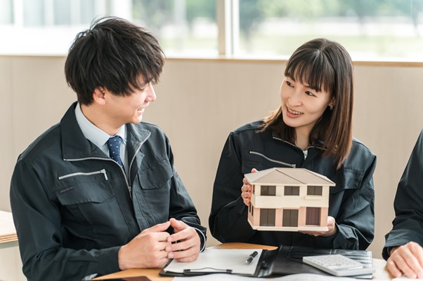 家の模型を持って話し合う男女