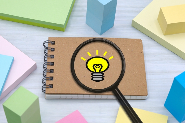 電球のイラストを拡大する虫眼鏡と、複数の付箋