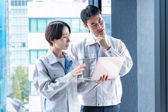 ノートパソコンを覗き込む作業服の男女