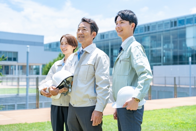 空を見上げる作業服の男女