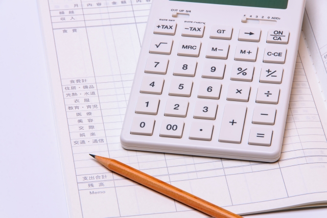 帳簿の上に乗る電卓と鉛筆