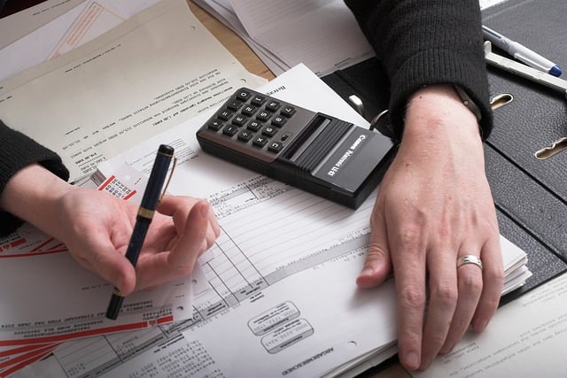 重なる書類の上でペンを持つ手